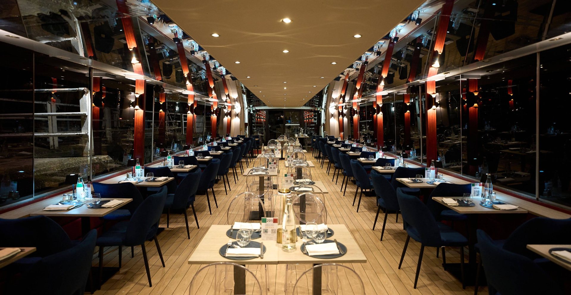 Salle de bateau-restaurant avec tables dressées et baies vitrées panoramiques